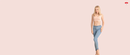 Woman wearing a comfortable nursing bra and jeans standing against a soft pink background